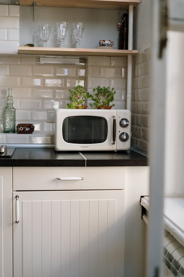 A cozy retro kitchen featuring a white vintage microwave and potted plants.